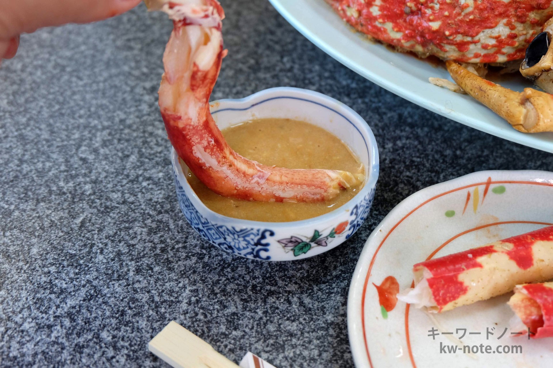 蟹味噌ダレにつけて高足ガニの脚の身を食べる